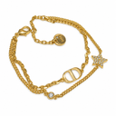 Gold-tone double-layer chain bracelet with a polished oval letter motif, a stone-set star and a round clear-stone accent. White background.