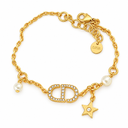 Gold-tone chain bracelet with a stone-set oval letter motif, two pearl-style beads and a dangling star charm. White background.