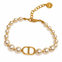 Pearl-style bead bracelet with gold-tone spacers and a polished oval letter motif. White background.