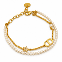 Double-layer bracelet combining pearl-style beads and a gold-tone chain, with a polished oval letter motif and a stone-set star. White background.